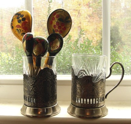Silver-plated podstakanniki with cut-glass inserts, and a bouquet of lacquered wood spoons in traditional Russian patterns.